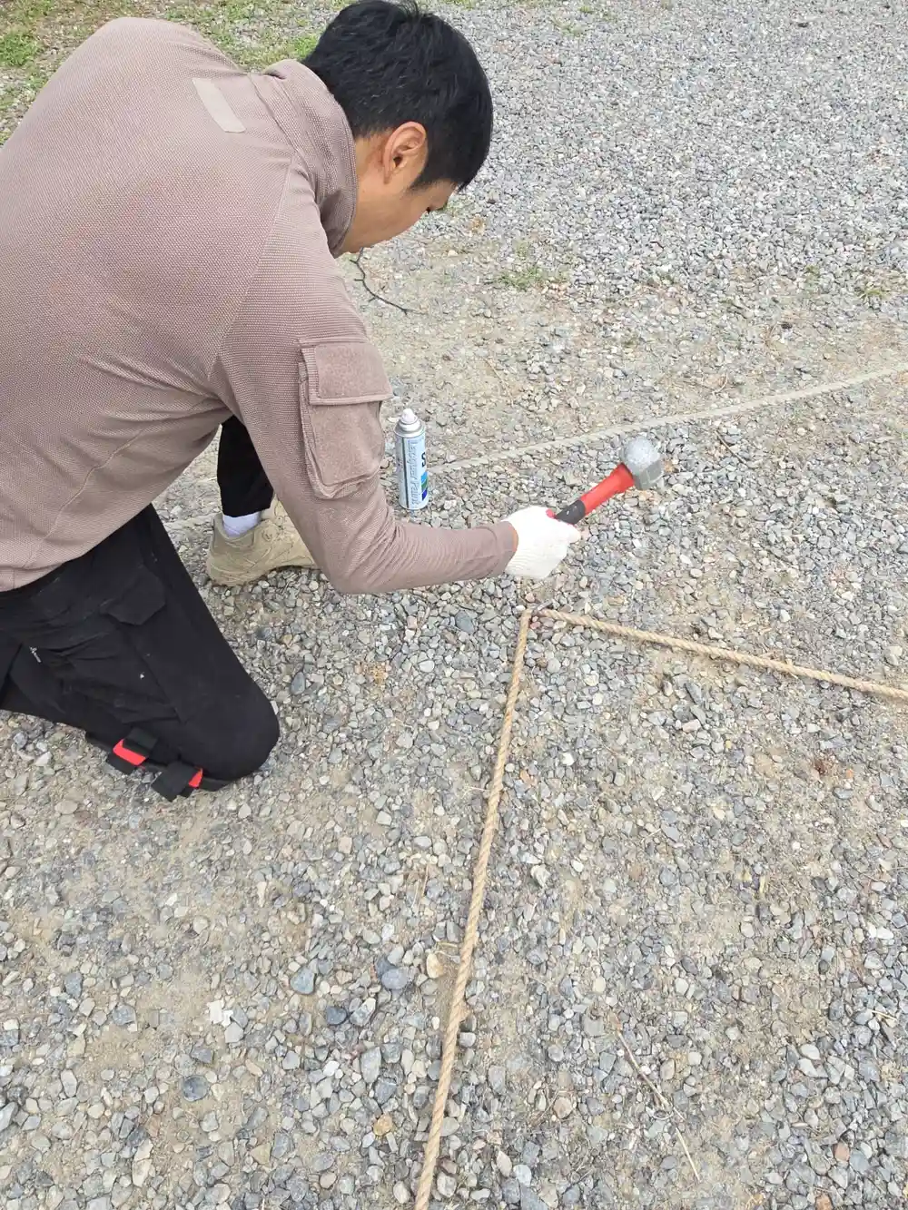 작업자가 망치로 말뚝을 땅에 박는 모습